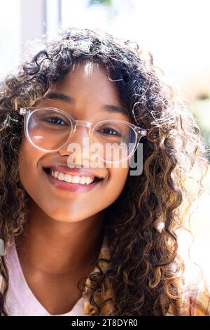 Portrait d'adolescente biracial heureuse assise sur le rebord de la fenêtre au-dessus du jardin à la maison Banque D'Images