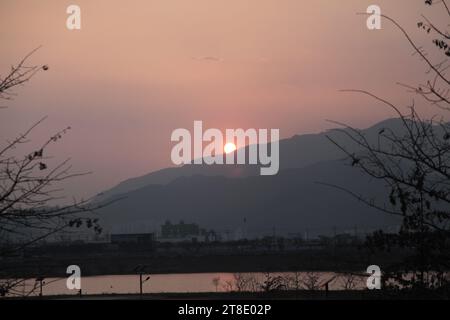 Un beau paysage pittoresque d'un coucher de soleil sur les montagnes lointaines, reflétant ses rayons de lumière dorés Banque D'Images
