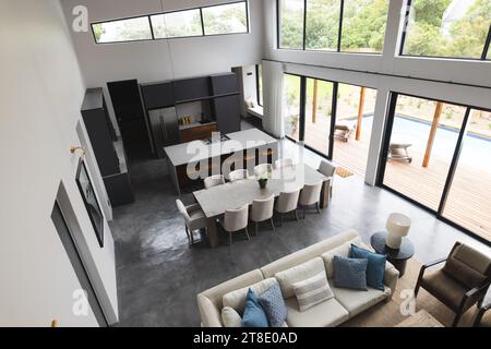 Grande cuisine moderne vide et salon avec table en bois, grand canapé blanc et grandes fenêtres Banque D'Images