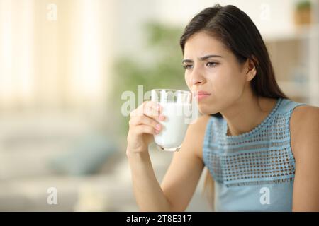 Femme dégoûtée sentant le lait expiré à la maison Banque D'Images