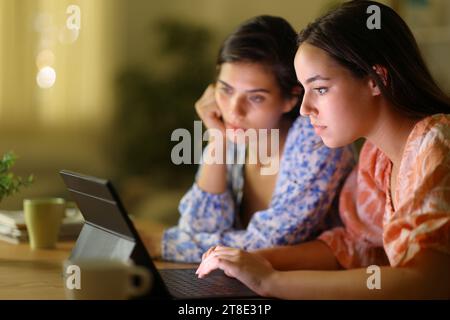 Deux femmes vérifiant le contenu de la tablette la nuit à la maison Banque D'Images