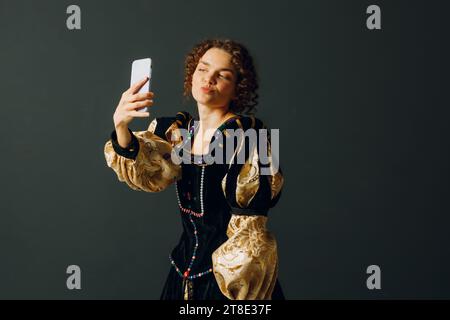 Portrait d'une jeune femme aristocratique tenant un téléphone portable vêtue d'une robe médiévale faisant un selfie shot Banque D'Images