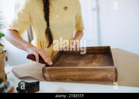 gros plan d'une artisan ponçant une boîte en bois de couleur wengé Banque D'Images