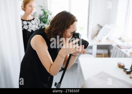 Une fille avec un appareil photo sur un trépied filme avec enthousiasme le processus créatif Banque D'Images