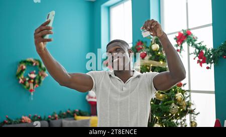 Homme afro-américain célébrant noël faire selfie par smartphone tenant la clé à la maison Banque D'Images