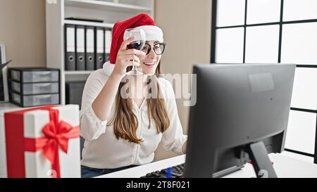 Jeune belle femme hispanique travailleur d'affaires célébrant noël ayant l'appel vidéo toasting avec du vin au bureau Banque D'Images
