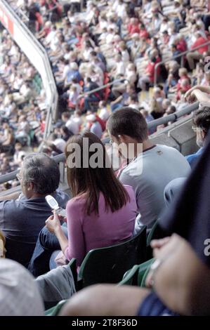 Un jeune couple textant sur des téléphones mobiles pré-smartphone à l'ancienne dans la foule pour le rugby pays de Galles v Angleterre au Millenium Stadium, août 23 2003. Photographie : ROB WATKINS Banque D'Images