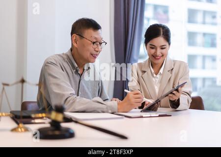 L'avocate explique la durée et l'accord juridique tandis que l'homme d'affaires senior signant le contrat sur tablette. Banque D'Images