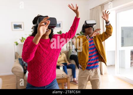 Heureux groupe diversifié d'amis adolescents utilisant des casques vr et jouant à la maison Banque D'Images