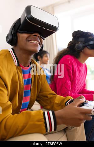 Heureux groupe diversifié d'amis adolescents utilisant des casques vr et jouant à la maison Banque D'Images