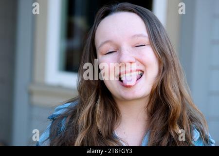 Enfant sassy montre son côté stupide en posant avec une langue dehors et drôle visage très heureux jour. Photo de haute qualité Banque D'Images