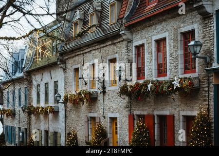 Une rue européenne enchanteresse ornée de décorations festives de Noël, y compris des couronnes, des guirlandes et des lumières scintillantes sur un bâtiment historique en pierre Banque D'Images