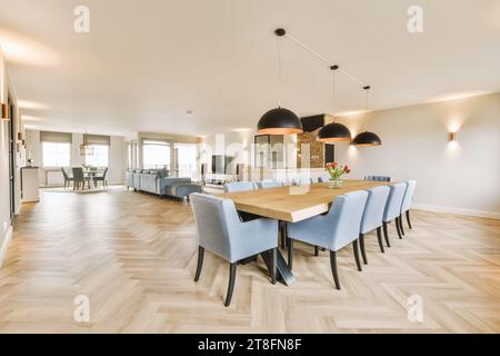 Lampes suspendues suspendues au-dessus d'une table à manger en bois avec des chaises bleues dans la salle à manger spacieuse de l'appartement luxueux Banque D'Images