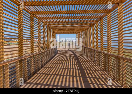 Lisbonne, Portugal : 01 octobre 2023 : Homme marchant dans un passage en bois près du pont Vasco da Gama et du Tage, Lisbonne, Portugal Banque D'Images