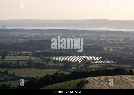 Des champs de panneaux solaires se dressent à côté de l'autoroute M5 à Michael Wood dans la campagne du Gloucestershire, avec l'estuaire de la Severn et la forêt de Dean Banque D'Images