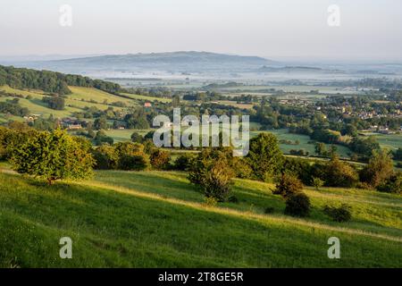 La lumière de l'aube tombe sur le paysage brumeux de la vallée d'Evesham, vu de Broadway Hill sur le Cotswold Edge dans le Worcestershire. Banque D'Images