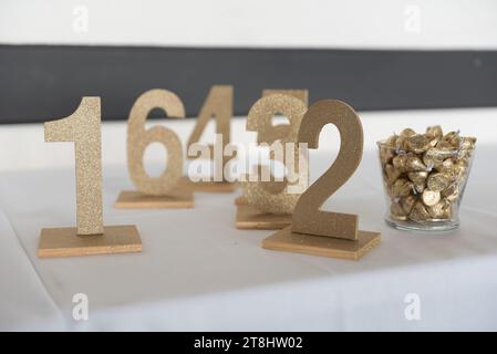 Trois panneaux de numéro de table en métal doré disposés sur une surface blanche Banque D'Images