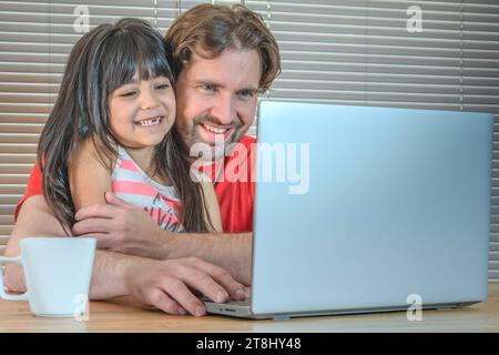 Portrait d'un père et de sa fille riant devant l'ordinateur. Banque D'Images
