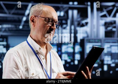 Technicien sénescent dans une ferme de minage de crypto-monnaie avec des serveurs spécialisés utilisant la technologie blockchain. Gestionnaire de centre de données inspectant les plates-formes asic résolvant des opérations de calcul complexes dans des installations de haute technologie Banque D'Images