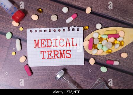 Cahier blanc avec DES TERMES MÉDICAUX en texte rouge et un stéthoscope sur une table en bois gris. Concept médical Banque D'Images