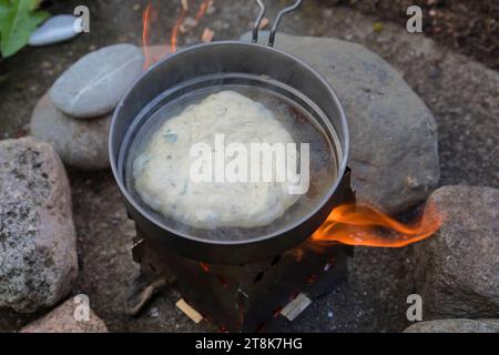 fabrication de bannock, est cuit sur feu ouvert, la pâte à pain est formée et cuite dans une casserole sur un cuiseur de camp, photo de série 5/5 Banque D'Images