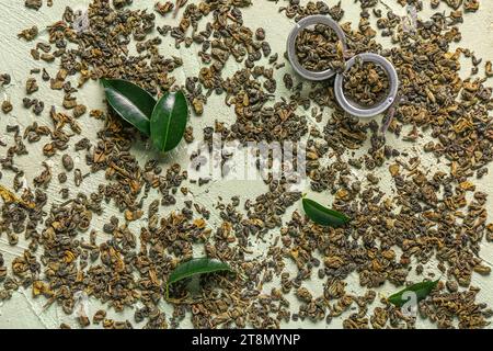 Infuseur en métal avec du thé vert et des feuilles fraîches sur fond vert grunge Banque D'Images