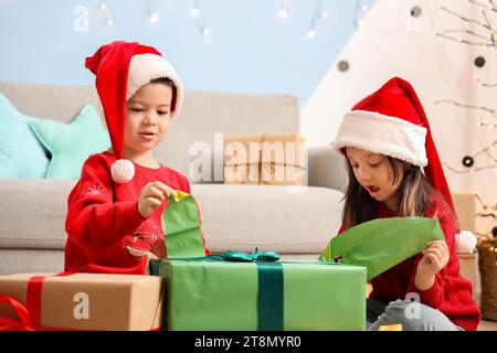 Adorables petits enfants ouvrant cadeau de Noël à la maison Banque D'Images