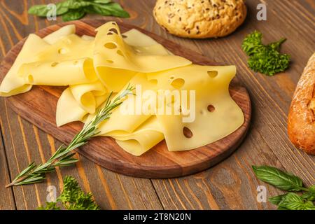 Planche avec de savoureuses tranches de fromage et du pain sur fond de bois, closeup Banque D'Images