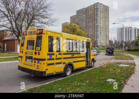 Un autobus scolaire jaune stationné sur le côté d'une route avec des immeubles d'habitation en arrière-plan Banque D'Images