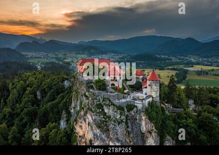 Bled, Slovénie - vue aérienne du magnifique château de Bled (Blejski Grad) avec un spectaculaire coucher de soleil doré sur les Alpes juliennes en arrière-plan Banque D'Images