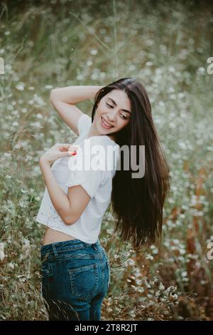 Heureuse jeune femme regardant par-dessus l'épaule dans le champ Banque D'Images