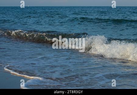 Une grande et forte onde de tempête de couleur turquoise avec des éclaboussures de mousse blanche coule et se brise sur le rivage. Banque D'Images