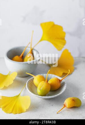 Fruits de ginkgo mûrs bio feuilles jaunes fraîches en médecine traditionnelle chinoise. Supplément nutritionnel populaire. Espace de copie. Banque D'Images