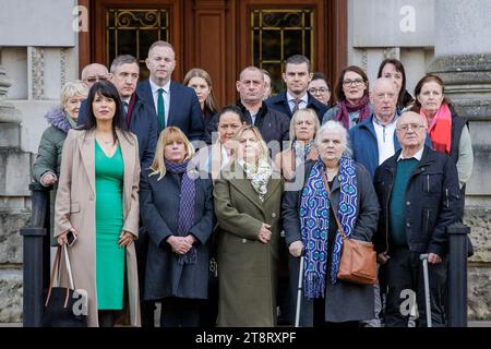 (Première rangée) Grainne Teggart, directrice adjointe d'Amnesty International pour l'Irlande du Nord, Martina Dillon, victime de troubles, Lynda McManus, Mairead Kelly, dont le frère était l'un des neuf hommes abattus à Loughgall, Co Armagh, en 1987, et John McEvoy, avec la famille et les partisans sur les marches de la haute Cour de Belfast devant les cours royales de justice avant une audience pour une contestation judiciaire intentée par les victimes du conflit nord-irlandais contre la loi sur les troubles largement opposée du gouvernement britannique. Date de la photo : mardi 21 novembre 2023. Banque D'Images