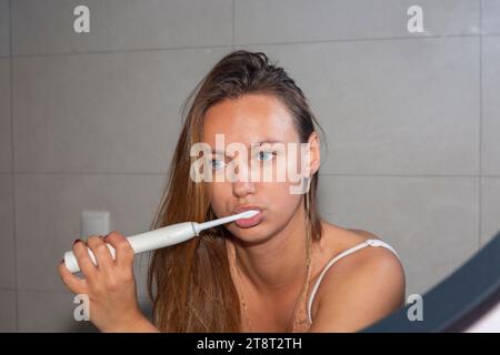 jeune femme se brossant les dents avec une brosse à dents électrique Banque D'Images