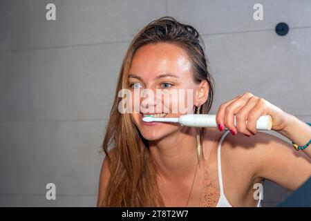 belle femme se brossant les dents avec une brosse à dents électrique Banque D'Images