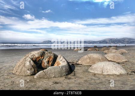 Plage de Moeraki Boulders. Otago, les Moeraki Boulders sont un groupe de grandes «pierres» sphériques sur la plage de Koekohe près de Moeraki sur la côte néo-zélandaise d'Otago. Ces rochers sont en fait des concrétions qui ont été exposées par l'érosion du rivage à partir des falaises côtières. Même aujourd'hui, il y a encore des rochers qui restent dans le mudstone qui finiront par tomber sur la plage lorsqu'ils perdront à cause de l'érosion Banque D'Images