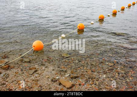 Bouées sphériques orange sur une corde dans la mer, clôturant une zone de baignade sûre Banque D'Images