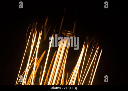 Filament de tungstène d'une vieille lampe incandescente dans l'obscurité, photo macro avec flou sélectif Banque D'Images