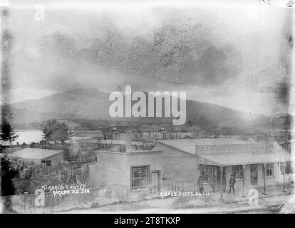 Mont Karioi de Raglan, Nouvelle-Zélande, 1911, vue du Mont Karioi de Raglan, Nouvelle-Zélande avec les locaux commerciaux d'Albert R Langley (agent foncier) et de M E Baker (magasins généraux) au premier plan, photographié en 1911, probablement par Gilmour Brothers Store, Raglan, Nouvelle-Zélande (Robert Gilmour, propriétaire Banque D'Images