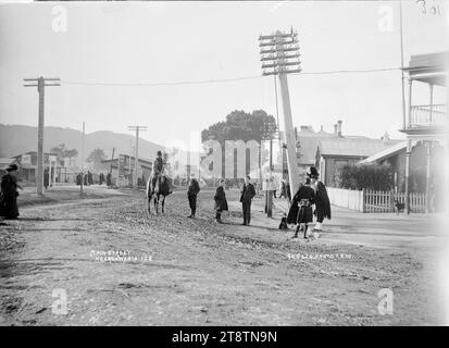 Great South Road, Ngaruawahia, Nouvelle-Zélande, 1910 -, Great South Road, la rue principale de Ngaruawahia, Nouvelle-Zélande. Sur la droite, les locaux commerciaux de Green & Colebrook sont partiellement visibles. Au premier plan, il y a deux membres d'une bande de pipe, portant des kilts, l'un portant un busby ; un homme sur un cheval, et trois jeunes hommes regardent vers la caméra. (Probablement Green & Colebrook, marchands, avec une succursale à Ngaruawahia, en Nouvelle-Zélande Banque D'Images