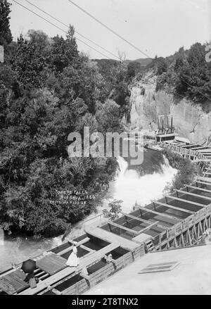 Centrale électrique à Okere Falls, district de Rotorua, deux femmes voyantes debout sur un broadwalk au sommet du déversoir de dérivation sur le site de la centrale électrique à Okere Falls sur la rivière Kaituna. ca 1908 regardant en amont et en bas du déversoir et de la cascade d'un point de vue au-dessus de la centrale électrique Banque D'Images