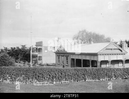 Les maisons pour hommes et femmes, Thames, la maison pour hommes et la maison pour femmes (maisons de district), Thames. Un bâtiment en bois d'un étage (pour hommes) et un bâtiment en bois de deux étages (pour femmes) situés dans un jardin formel entouré d'une haie à faible croissance. Il y a un poteau de drapeau dans le jardin avant. Un homme âgé se tient devant la maison des hommes. au début des années 1900 Banque D'Images