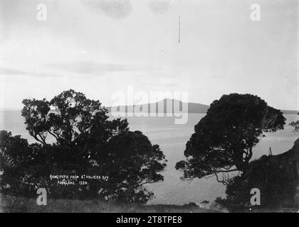 Vue de l'île de Rangitoto depuis la baie de St Heliers, vue de l'île de Rangitoto depuis les environs de Cliff Road, St Heliers. Les Pohutukawas sont au premier plan, poussant sur la falaise à l'extrémité est de la baie. au début des années 1900 Banque D'Images