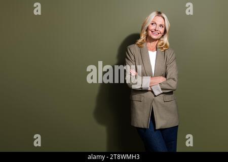 Photo de femme d'affaires senior confiant souriant les bras croisés à la recherche de nouveaux défis idées intelligentes isolées sur fond de couleur kaki Banque D'Images