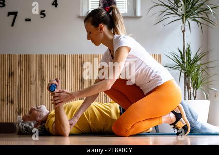 Jeune femme physiothérapeute professionnelle workng avec un homme âgé pour l'aider à se réadapter. Lui apprendre la posture correcte des exercices et l'utilisation de Banque D'Images
