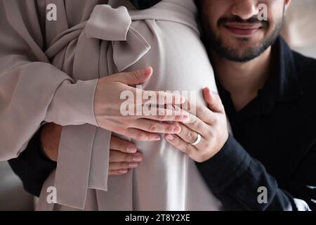 L'homme arabe écoute le ventre de sa belle femme enceinte et sourit Banque D'Images