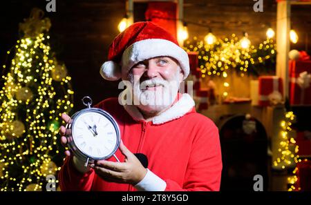 Joyeux Noël et bonne année. Le Père Noël fête Noël ou le nouvel an. Père Noël souriant avec réveil. Veille de Noël. Homme barbu au Père Noël Banque D'Images