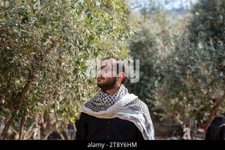 portrait pour homme portant keffiyeh dans le champ d'oliviers avec fond noir et chemises noires également avec expression faciale en colère Banque D'Images