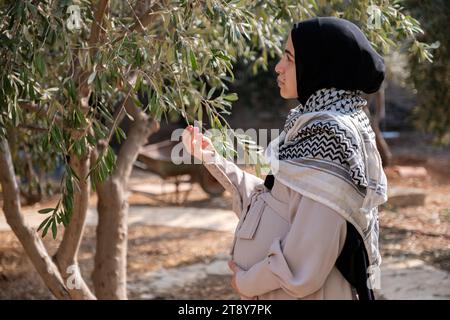 Femelle tenant une branche d'olivier tout en portant du keffiyeh palestinien dans le champ Banque D'Images